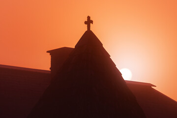 Dawn and rising sun behind the medieval church roof in Bohinj municipality, Slovenia