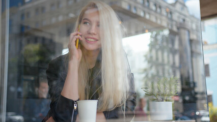 Fototapeta premium Mixed race smiling woman sitting in a cafe and talking on the phone