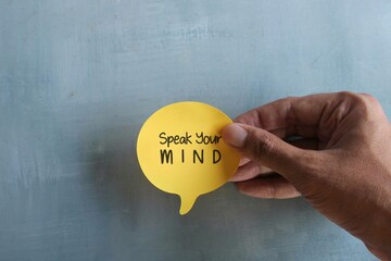 Top view image of hand holding speech bubble with text Speak Your MIND. Motivational quotes concept