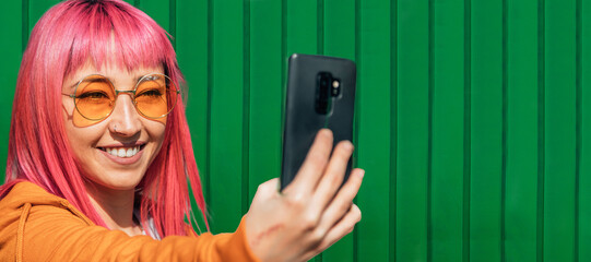 asian girl making a selfie with the mobile phone on the green wall