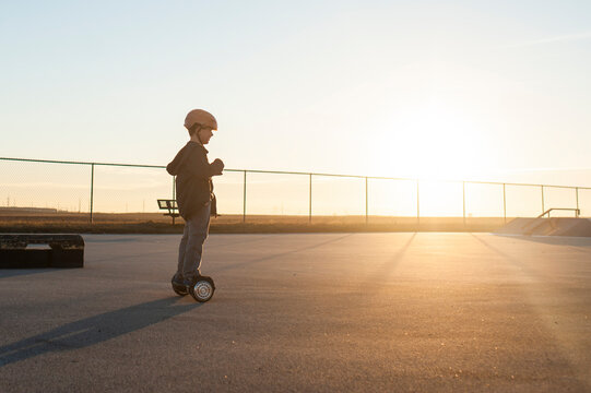 Little boy riding hover board in hazy winter light at skate park