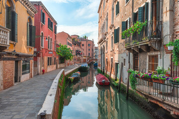 Venice, Italy. View on Venetian medieval street with old colorful buildings and bridge over water canal with boats
