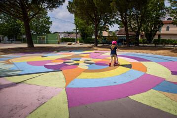 Child rides scooter in colorful painted outdoor park