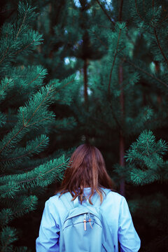 Back view of unrecognizable woman  with backpack in forest.