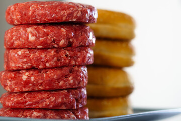 stack of raw beef burgers with their buns
