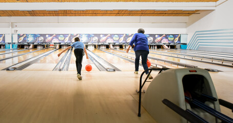 Older woman and child bowling together at a bowling alley.