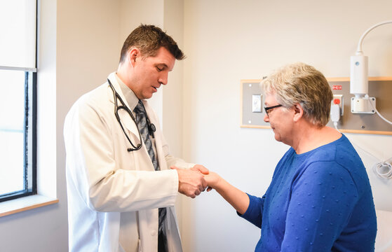 Doctor Examining The Hand Of Older Patient In A Clinical Setting.