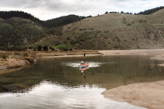 Two kids in a kayak paddling in a river in New Zealand