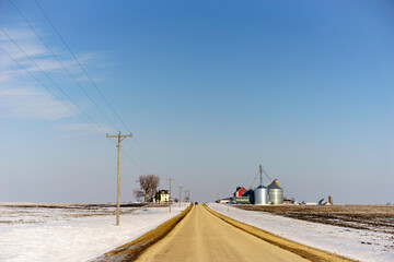 Straight road with approaching car in wintry Midwestern farm country
