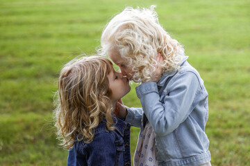 sisters giving each other kiss standing in field