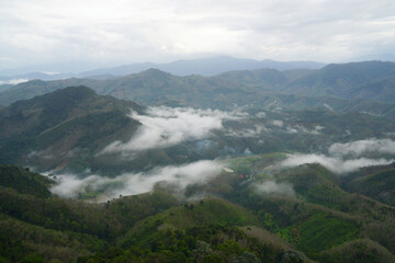 Fototapeta na wymiar Landscape Green nature fog and misty cover around mountain valley seen from Skywalk Aiyerweng Famous landmark in Betong Yala southern thailand - in the morning - Travel and Sighseeing South east Asia 