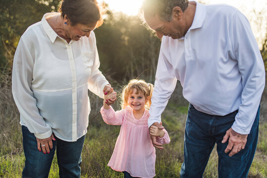 Portrait of grandparents holding little girls hand in field