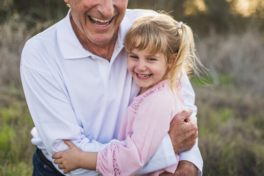 Grandfather hugging young granddaughter and laughing