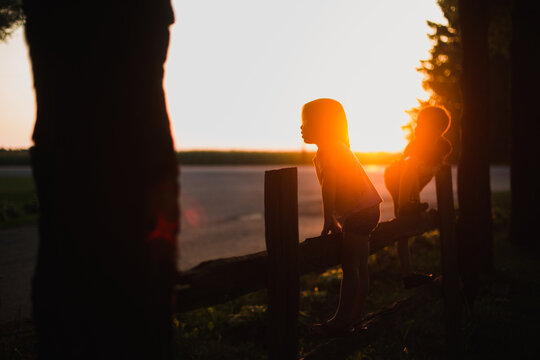 children on a fence with the setting sun