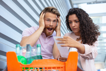 young couple standing with cart and shopping list