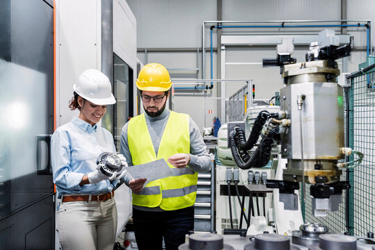 Smiling engineer consulting with colleague in factory
