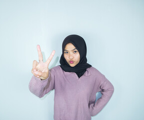 Close-up portrait of nice attractive cheerful muslimah lady showing v-sign isolated over light grey...
