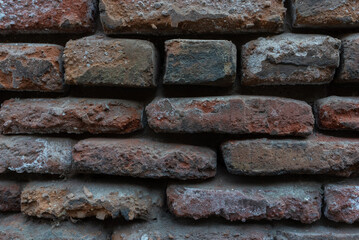 Texture of old brickwork with holes. Dark red brick wall in the old city. Horizontal photo close up