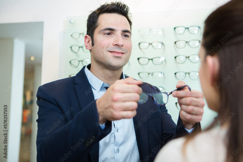 Sticker man offering glasses to customer at an optical center