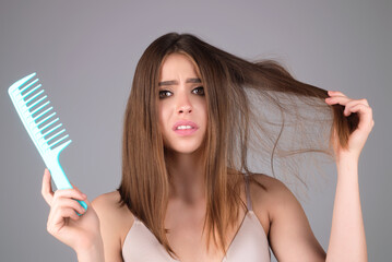 Young woman with hair loss problem worried about hairloss. Messy bed hair. Problem with tangled hair. Worried girl with damaged hair. Hairloss problem. Portrait of woman with a comb and bad hairs.