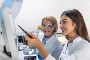 Two Research Scientists Programm Medical Equipment with Tablet Computer. Team of Professionals...