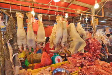 A detailed shot of the meat at butcher's stall in Chow Kit Road Market, Kuala Lumpur. The scene is bustling with vendors shouting out their offerings and people pushing for space in the crowded stalls