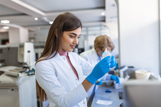Female Medical Research Scientist Looks at Biological Samples Before Analysing it Under Digital Microscope in Applied Science Laboratory. Lab Engineer in White Coat Working on Vaccine and Medicine - Powered by Adobe