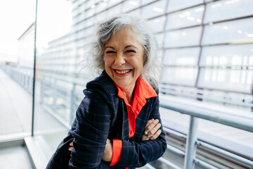 Happy mature businesswoman with arms crossed at station