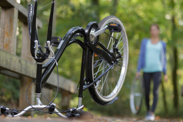 Fototapeta na wymiar female cyclist returning to upturned bicycle carrying wheel