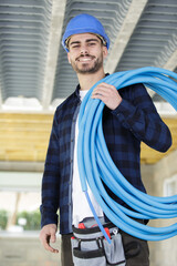 plumber holding reel of polyurethane pipe on shoulder