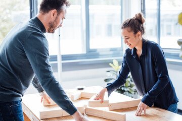 Smiling businesswoman with businessman arranging wooden blocks in office