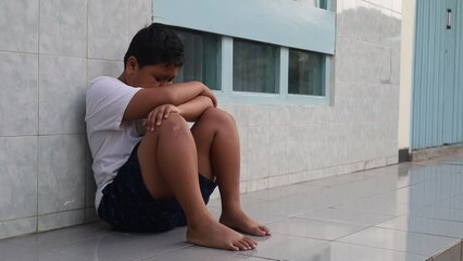 Depressed boy sitting on the terrace floor