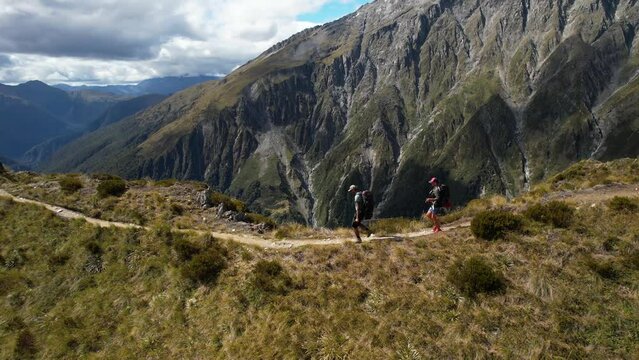 Young couple hikers walking on mountain ridge with backpack, New Zealand adventure. Aerial drone