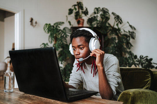Freelancer wearing headset sitting with laptop at home office