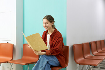 Happy woman reading medical results sitting on chair at clinic