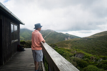 Fototapeta na wymiar A backpacker looking at the views from Pouakai hut, Pouakai circuit track, Egmont national Park.