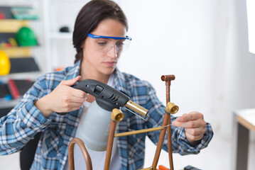 Fototapeta na wymiar female professional plumber welding and soldering copper pipes