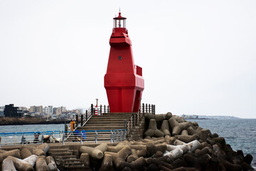 Iho Tewoo red pony horse Lighthouses and tetrapod for breakwater and wave water dissipating prevent erosion in sea ocean at Iho Tewoo beach for korean people travel visit at Jeju Island, South Korea