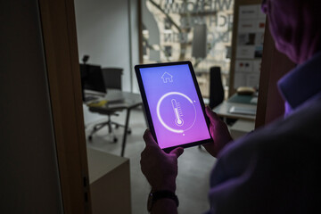 Businessman checking temperature through home automation app on tablet PC at office
