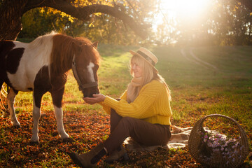 Beautiful woman and pony horse in autumn forest, sunset light, portrait, outdoor recreation, love...