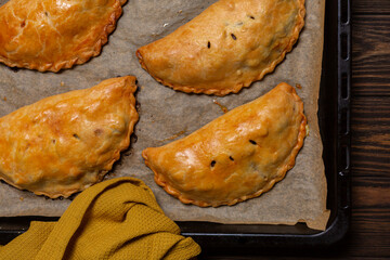 Just baked meat turnovers or pies, or empanadas, or cornish pasty on a baking tray.