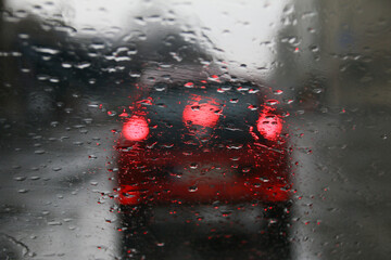 Durch regennasse Autoscheibe fotografierte Rücklichter eines Autos