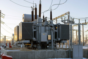 Power transformer at the substation with the rays of the morning sun. Energy. Cold winter dawn at the substation.