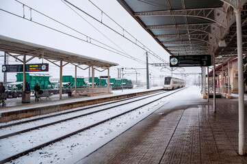 Fototapeta na wymiar Snowy Villena Train Station. Arrival of a train with snowy tracks.