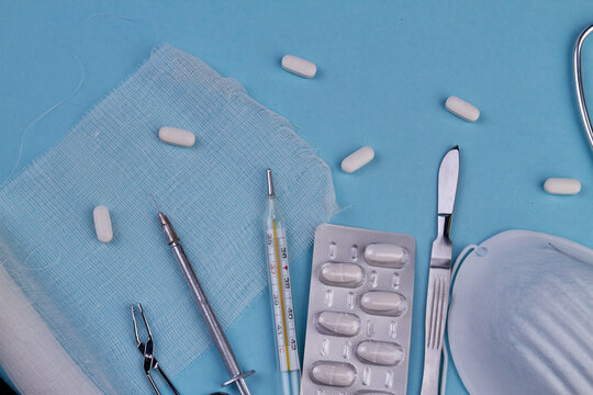 Top view of tools for cosmetological surgery. Pills and gause on blue background.