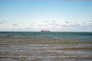  A breathtaking view of the sea with a large cargo ship visible on the horizon.