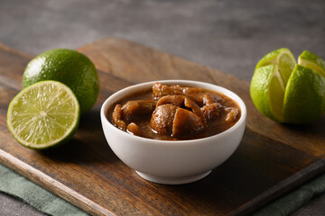 Traditional Sri Lankan Lime Pickle of lime, salt, chilli, pepper on brown background. Close up.