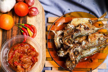 fried mackerel fish served on a plate with spicy sauce