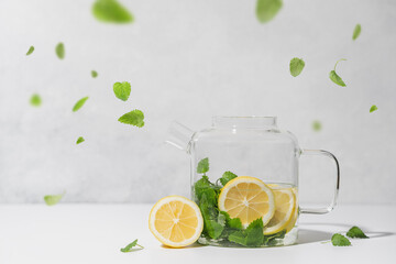 Melissa tea with lemon in glass teapot on white background. Natural, healthy tea concept