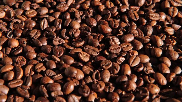 Coffee beans background. Texture of coffee beans close up. Dark brown roasted coffee is spinning. Abundance. Concept for coffee product advertising. Selective Focus. Border design with copy space